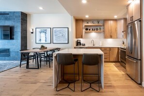 Een moderne keuken met een centraal eiland, houten kastjes en roestvrijstalen apparatuur.