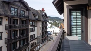 A multi-story building with balconies, a ski slope in the background, and a clear view of the surrounding landscape. - Wind-Walker | Includes Two 1-Day Lift Tickets (Tamarack)
