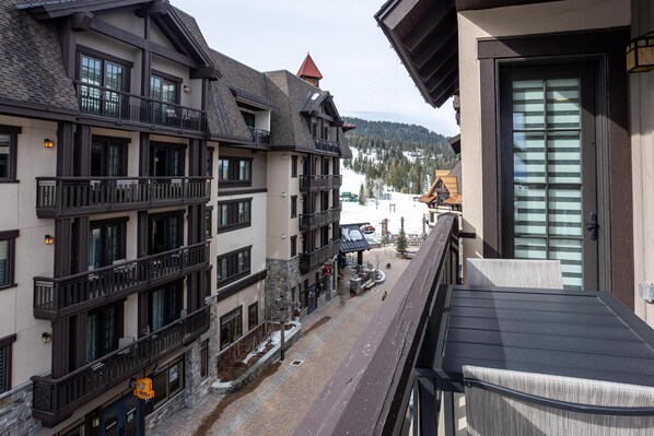 A multi-story building with balconies, a ski slope in the background, and a clear view of the surrounding landscape.