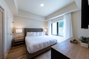 Une chambre d’hôtel moderne avec un grand lit, des tables de chevet, un bureau et une fenêtre avec des rideaux.