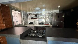 Una cucina con piano cottura a gas, forno a microonde, frigorifero e una finestra vista esterna.