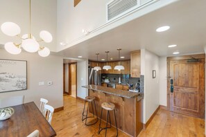 Una cocina moderna con una isla central, taburetes de bar, lámparas colgantes y armarios de madera.