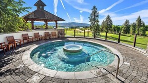 A hot tub surrounded by stone tiles, wooden chairs, and a gazebo overlooking a golf course. - Aspen Grove | Includes Two 1-Day Lift Tickets (Tamarack)