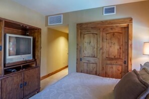 Une chambre à coucher avec un lit, une armoire en bois et un téléviseur posé sur un meuble.