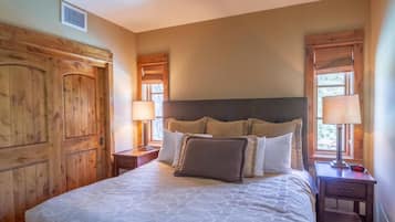 A bedroom with a large bed, wooden headboard, two bedside tables with lamps, and a wooden wardrobe.