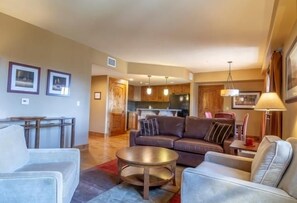 A modern living room with a sofa, armchairs, and a coffee table. There is a kitchen area visible in the background.