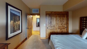 Une chambre avec un grand lit, une armoire en bois et un tableau encadré au mur.