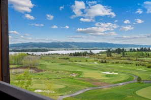 A golf course with a lake and mountains in the background.