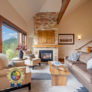 A cozy living room with a stone fireplace, comfortable seating, and a view of the outdoors. - Lake View Retreat|Includes Two 1-Day Lift Tickets (Tamarack)