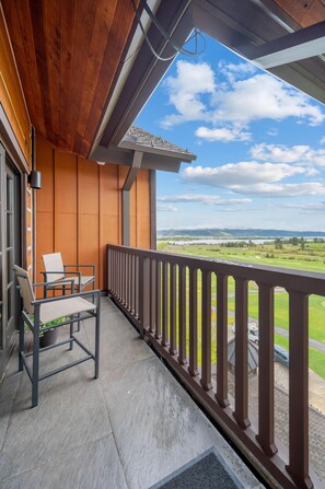 Un balcon donnant sur un terrain de golf, une chaise et un pot de fleurs.