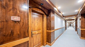 Un pasillo con paredes de madera, suelo alfombrado y una puerta marcada con el número 415.