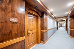 A hallway with wooden walls, a carpeted floor, and a door marked with the number 415. - Lake View Retreat|Includes Two 1-Day Lift Tickets (Tamarack)