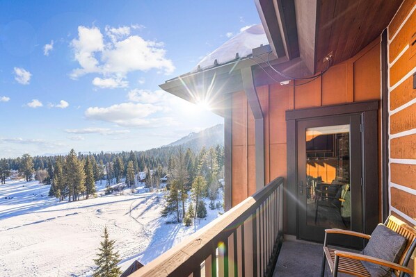 Ein Balkon mit Blick auf eine verschneite Landschaft und ein Gebirge.