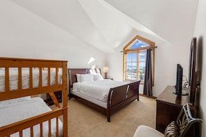 Ein Schlafzimmer mit Bett, Schreibtisch und einem Fenster mit Blick.