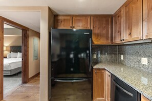 Eine kleine Küche mit Holdekor, einem schwarzen Kühlschrank und einer Arbeitsplatte aus Granit.