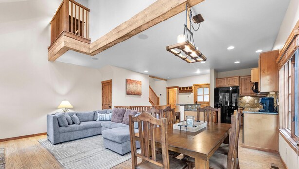 A spacious living room with a grey sofa, wooden dining table, and chairs. A staircase leads to an upper level. - Base Camp | Includes Two 1-Day Lift Tickets (Tamarack)