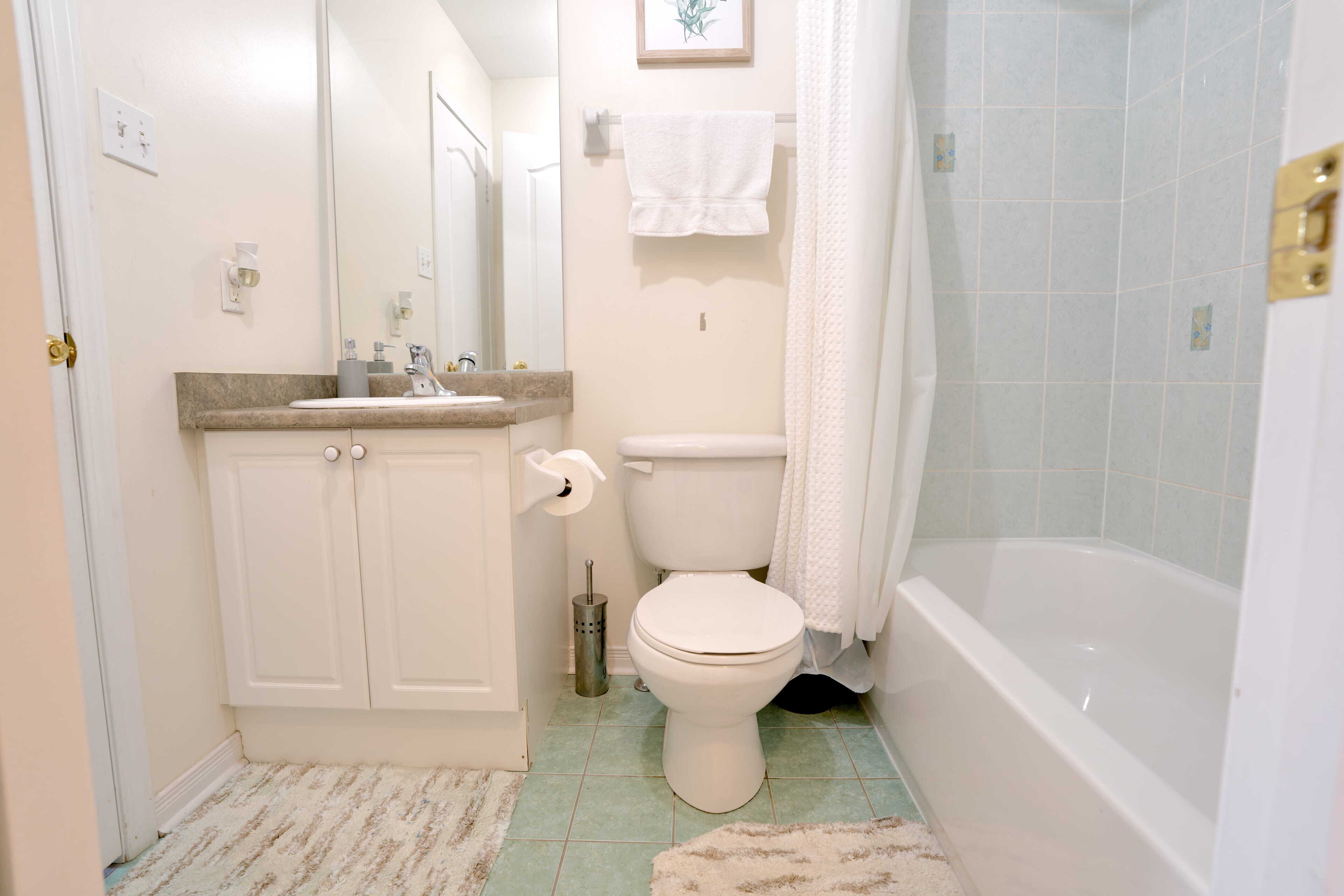 Et badeværelse med toilet, vask og badekar.
