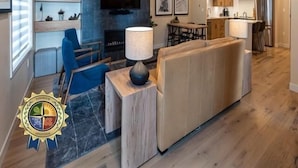 Una sala de estar moderna con un sofá, un televisor montado en la pared y una chimenea.