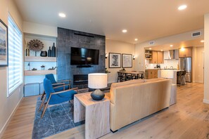 A modern living room with a TV, seating, and a fireplace.