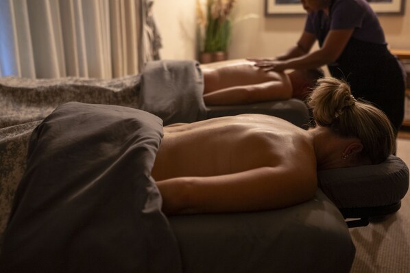 A massage therapy session in a room with a massage table, pillows, and a person receiving a back massage.