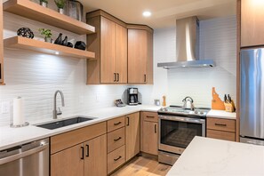 Una cocina moderna con armarios de madera, un refrigerador de acero inoxidable y un horno empotrado.