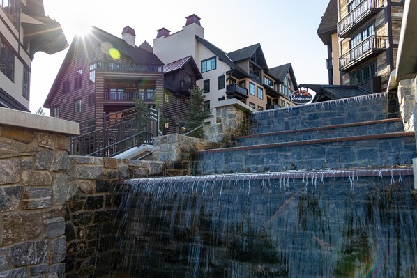A stone staircase leading to a wooden building with a waterfall feature.