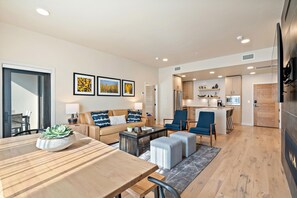 Una sala de estar moderna con sofá, mesa de centro y zona de comedor con mesa de madera.