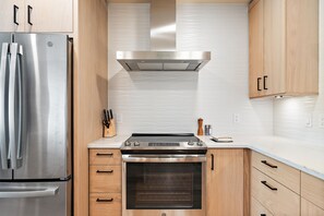 Una cocina moderna con electrodomésticos de acero inoxidable, armarios de madera y horno empotrado.