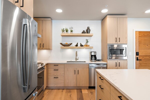 Una cocina moderna con electrodomésticos de acero inoxidable, armarios de madera y encimera de mármol.