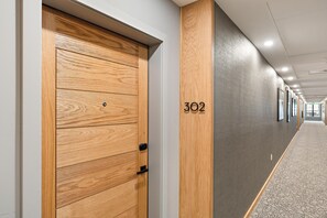 Un pasillo con una puerta de madera y el número '302' en la pared.