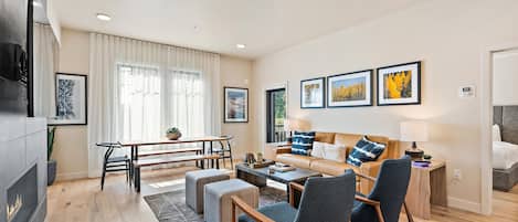 Una sala de estar moderna con sofá, sillas, una mesa de comedor y obras de arte en las paredes.