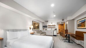 Habitación de hotel con una cama grande, un escritorio, una silla, un sofá y una kitchenette.