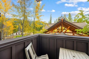 Eine Holzterrasse mit Blick auf einen Berg und Herbstbäume.