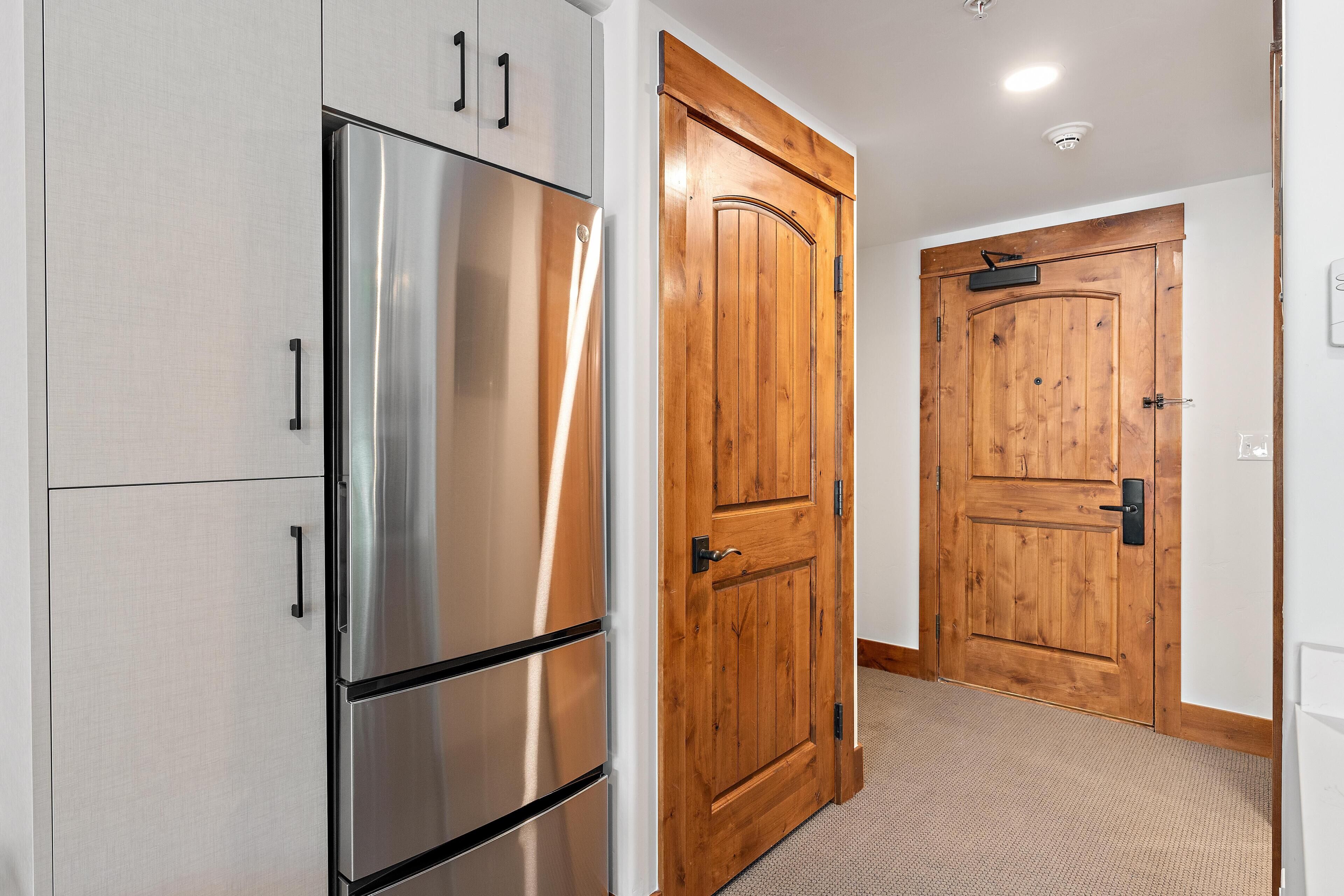 A kitchen with stainless steel appliances and wooden doors.