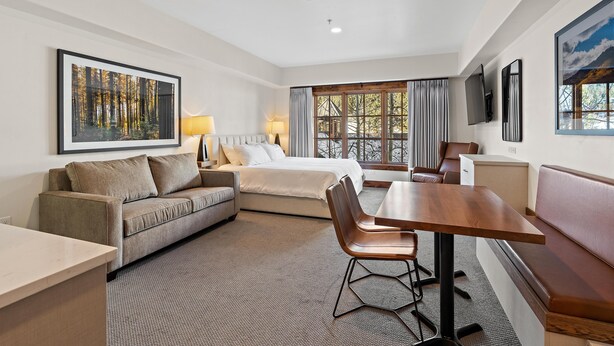 Une chambre d’hôtel avec un lit, un canapé, une table à manger et un téléviseur.