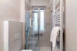 A modern bathroom with a glass-enclosed shower, a toilet, and a towel rack. - Luci A Lago (Como)