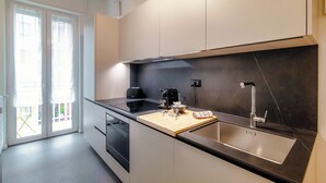 A modern kitchen with a black countertop, stainless steel sink, and a coffee maker. - Luci A Lago (Como)