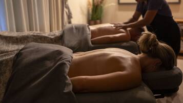 A massage therapy session in a room with a massage table, pillows, and a person receiving a back massage.