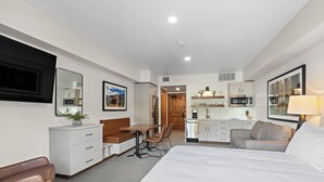 A hotel room with a bed, a desk, a chair, a sofa, a dining table, a kitchen area, and a bathroom. - Happy Loon | Includes Two 1-Day Lift Tickets (Tamarack)