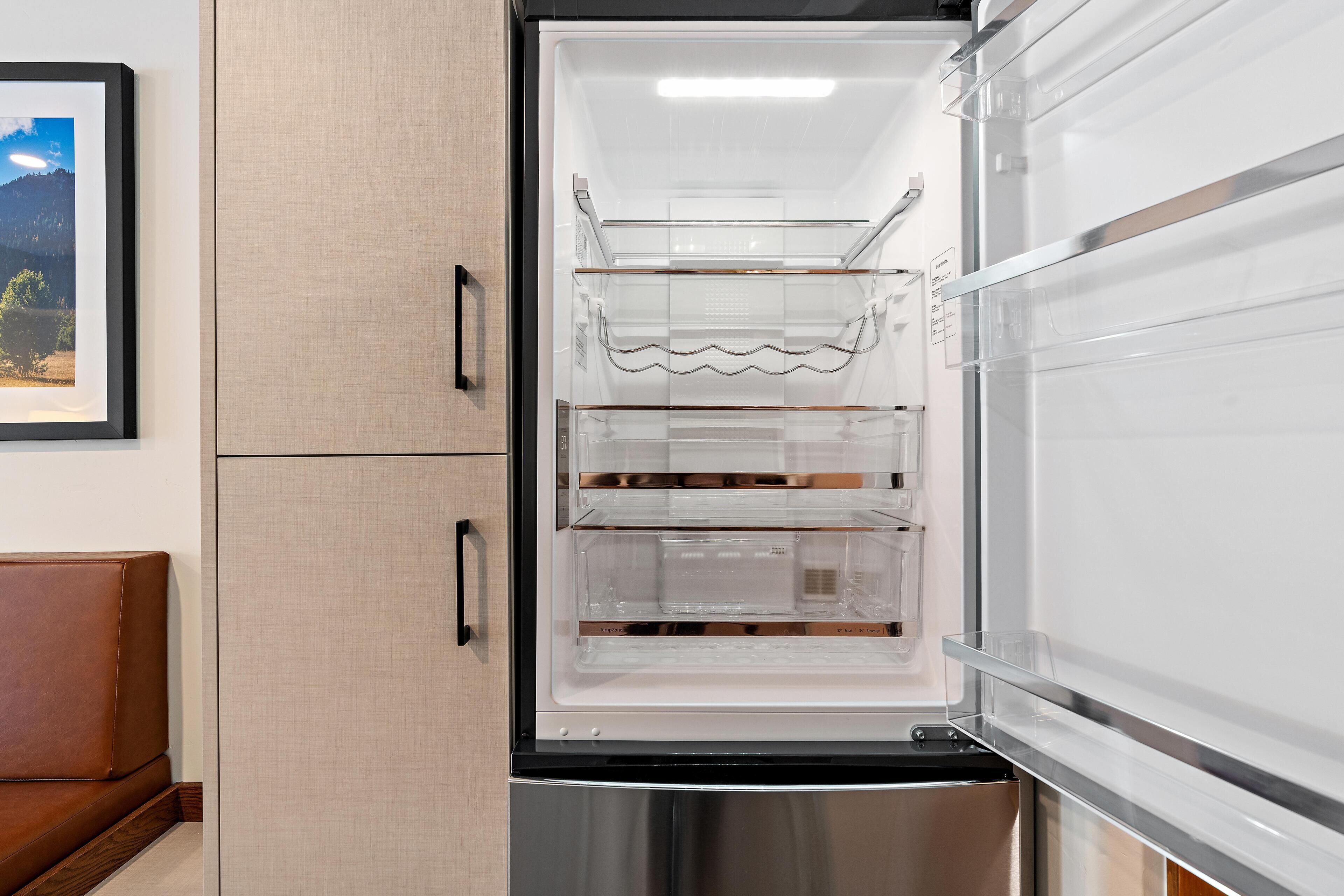 Un refrigerador abierto con estantes transparentes y un exterior de acero inoxidable.