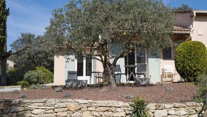 A stone wall, a tree, and a building with a balcony.