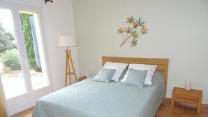 A bedroom with a bed, a nightstand, a lamp, and a window.
