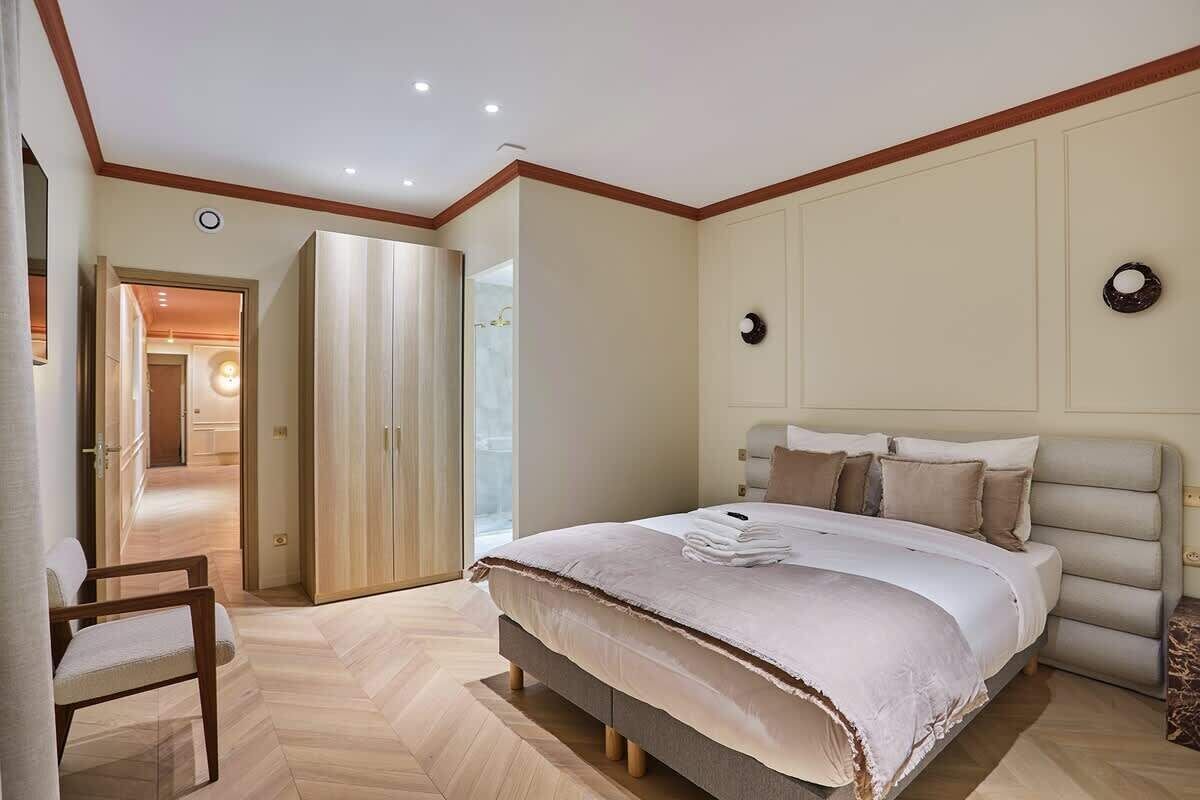 Une chambre avec un grand lit, une chaise et une armoire.