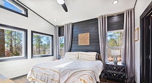 A bedroom with a large bed, a nightstand, and a window with curtains. - Game-Filled Retreat for Families and Friends (Broken Bow)