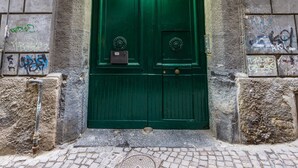 Uma porta verde com uma pequena caixa de correio e uma placa de identificação.