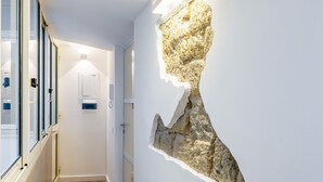 Um corredor com design moderno, destacando uma instalação artística única na parede e piso de madeira.