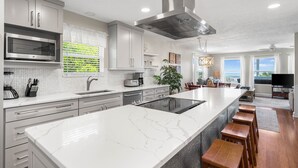 Een moderne keuken met een groot schiereiland, roestvrijstalen apparatuur en uitzicht op de woonkamer.