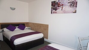 A hotel room with a large bed, a smaller bed, a nightstand, a chair, and a wall-mounted light fixture. - Accommodation London Bridge (London)