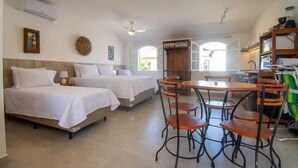 A hotel room with two beds, a dining table with chairs, and a kitchenette. - Bella Buzios Apartamentos (Búzios)