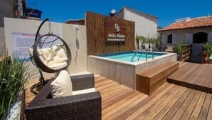 A pool area with a sign for Bella Buxes Apartments, outdoor seating, and a hanging chair. - Bella Buzios Apartamentos (Búzios)